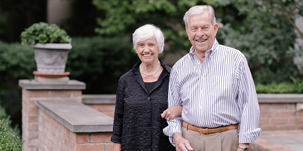 Anne Frost Wehrheim in a black shirt and Philip Wehrheim in a white and gray striped button-down outside their home in Pittsford.