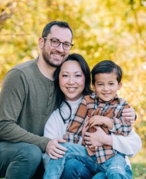 Mandy Agins, her spouse, and young child against a background of fall leaves