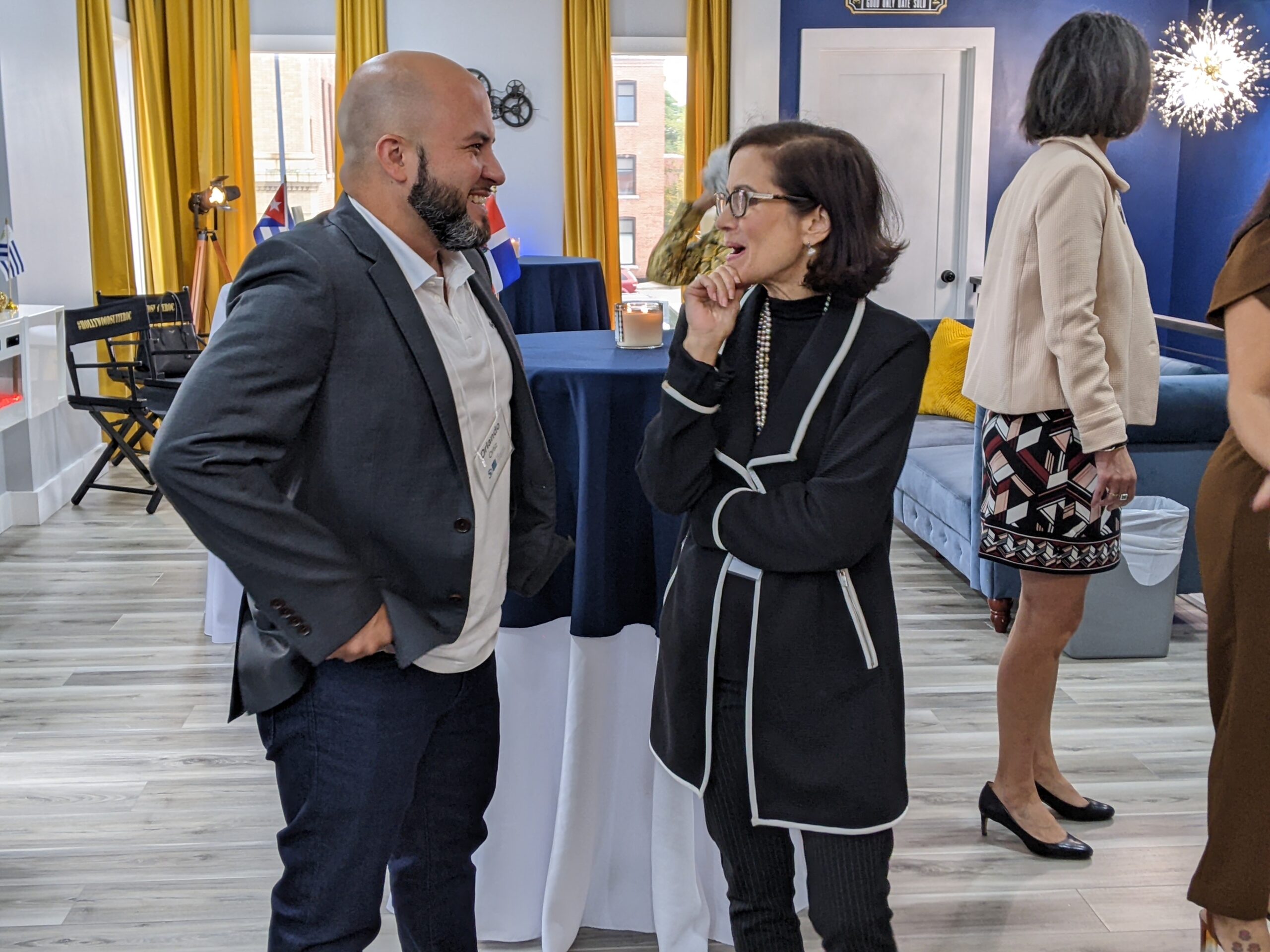 Two people wearing formal wear smiling and chatting at an event.