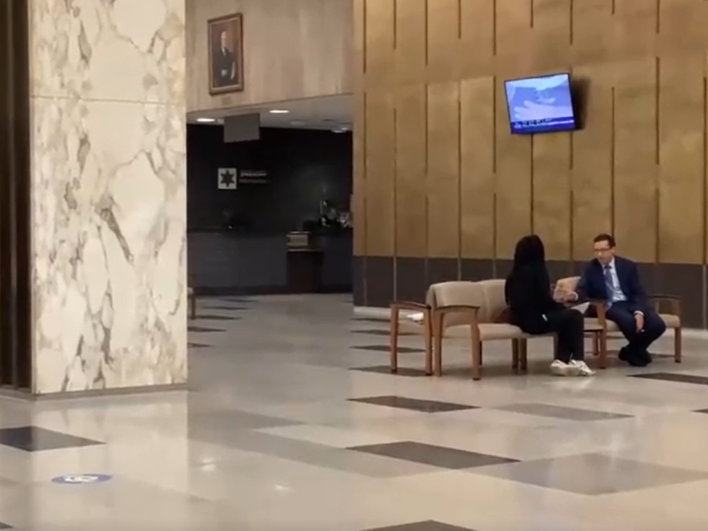 Two people talking in the Hall of Justice.