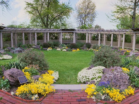 A colorful garden, lawn, wrapped by a semi-circular pergola.