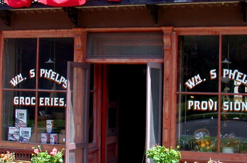 A red storefront that says Phelps Groceries and Provisions
