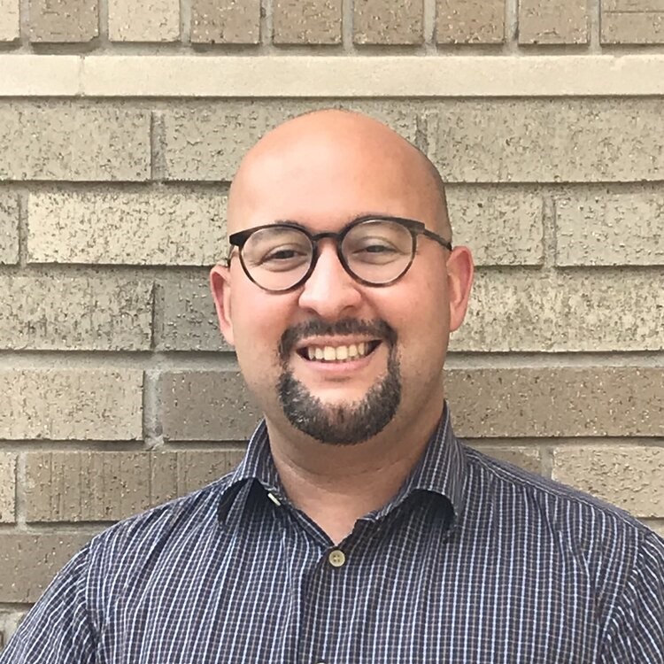 A man in glasses and a blue and white checkered shirt