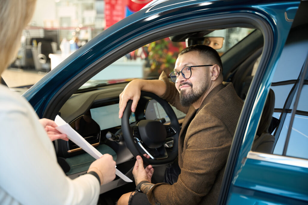 Man sitting behind the wheel of a car communicates with the seller