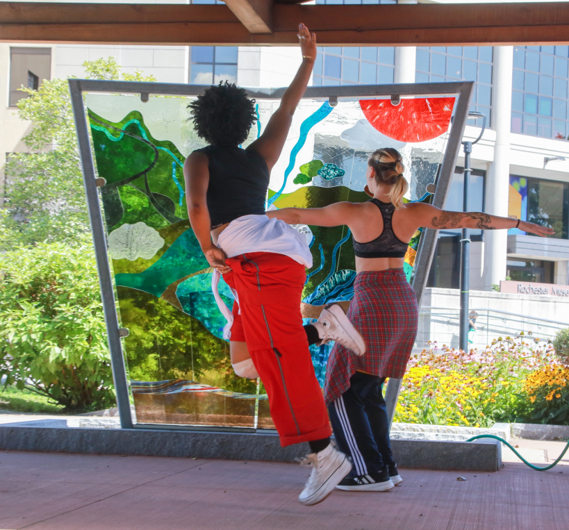 Two dancers in front of stained glass outdoors