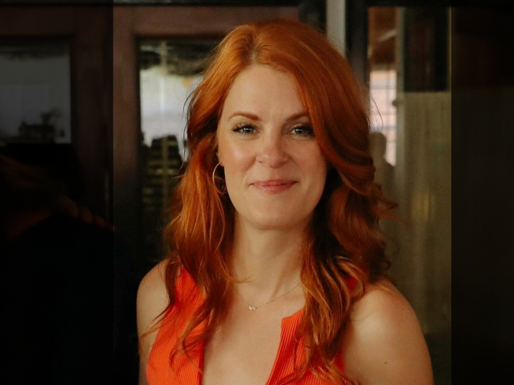 A woman with red hair and an orange shirt