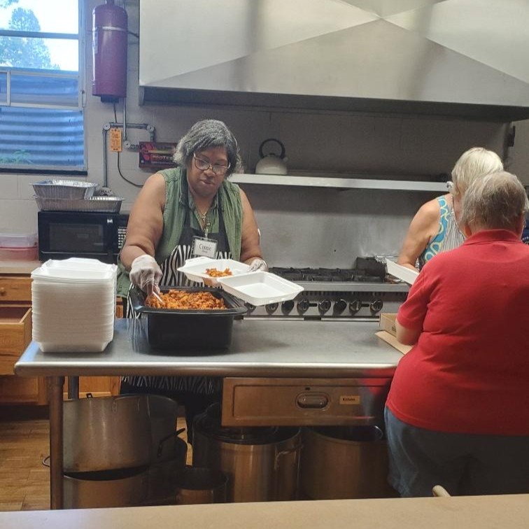 A woman in a kitchen serving food.