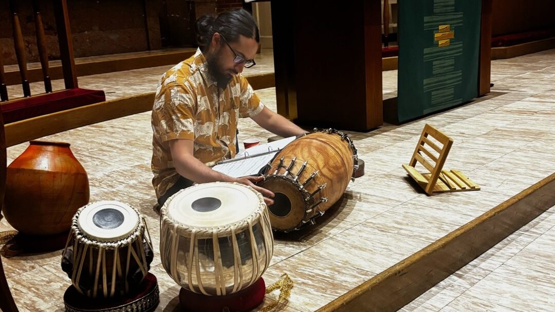 A man sitting on the floor with several drums.