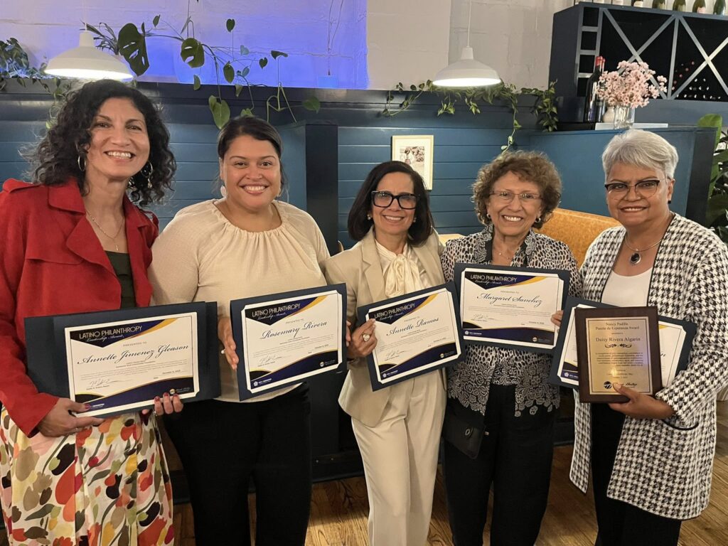 Annette in a red jacket stands with other women holding a certificate.