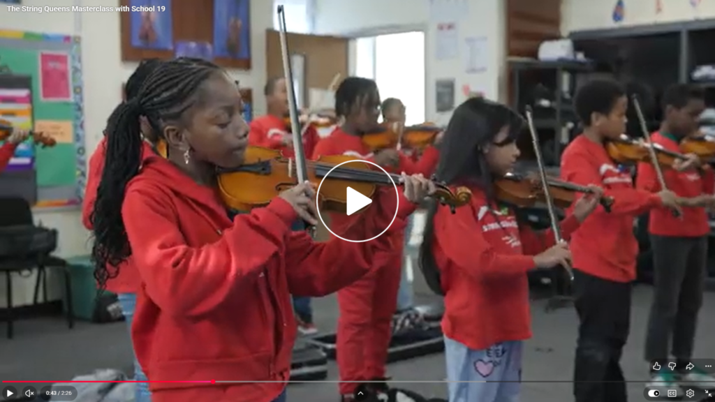 Young people in red shirts play violins in a classroom with Strings for Success, a program of Center for Youth.