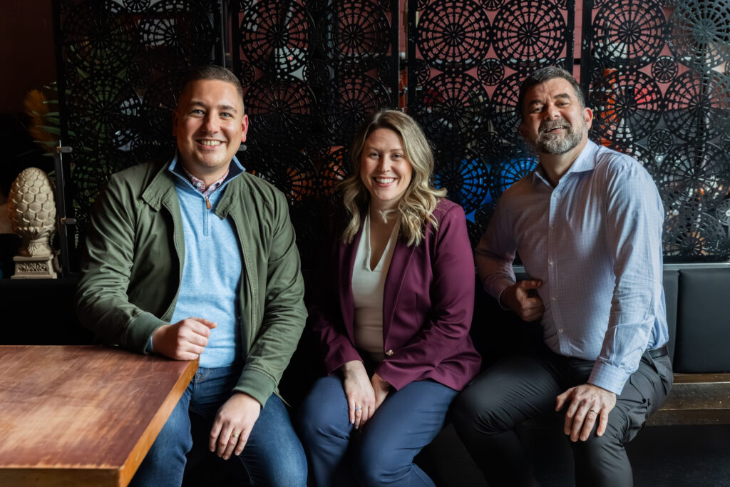 Three people in business attire front of an ornate black iron wall