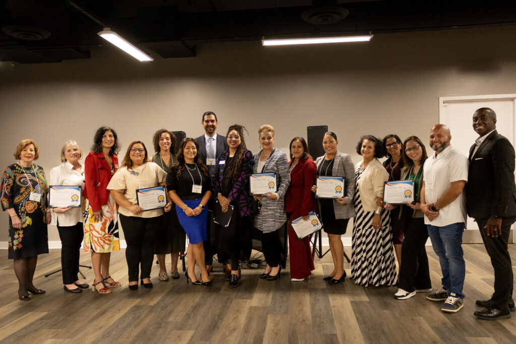 A large group of people, several of which are holding grant certificates from the Latino Giving Circle.