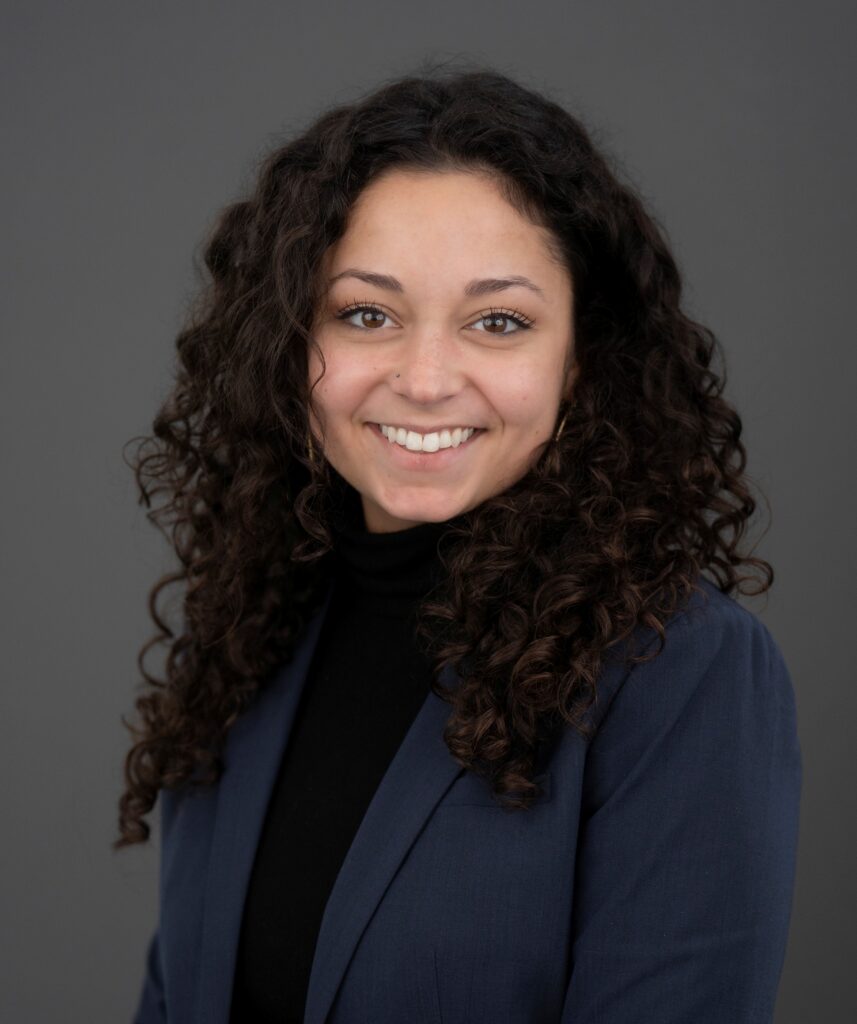 Miranda Santillo smiling and wearing a black shirt and a blue blazer.