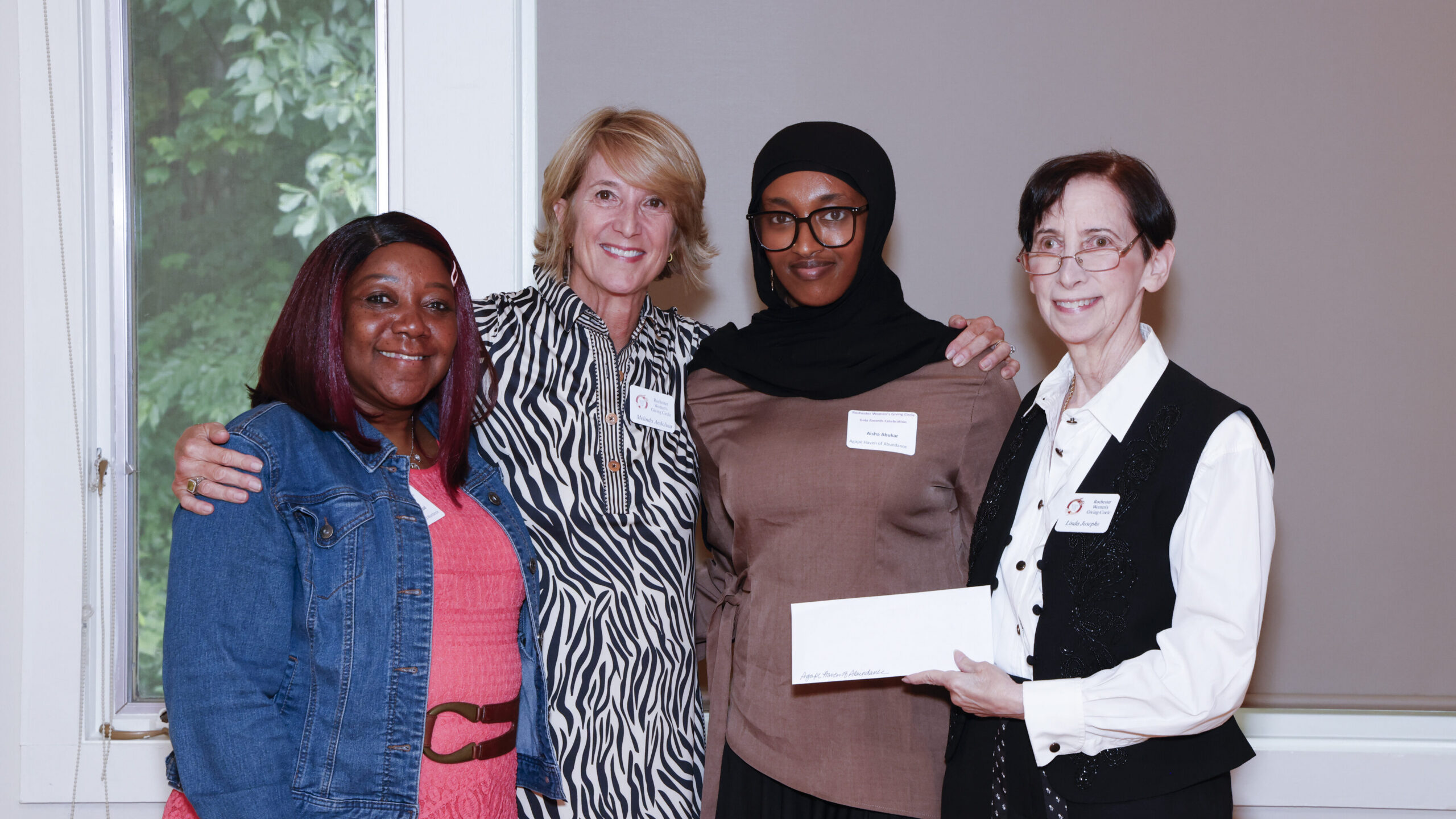 Four people in a row; one of them holding a check