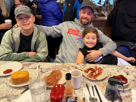 A man in a Bills sweatshirt and hat with two kids.
